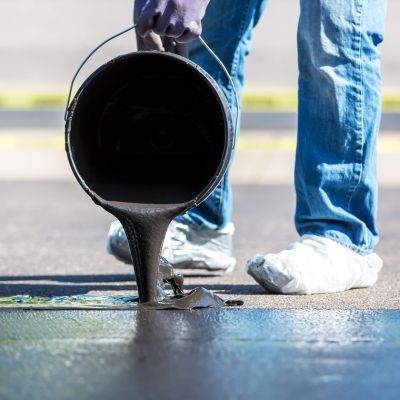 homme en train d'appliquer beton sur goudron